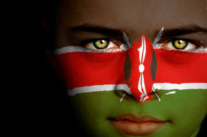 Portrait of a boy with the flag of Kenya painted on his face.